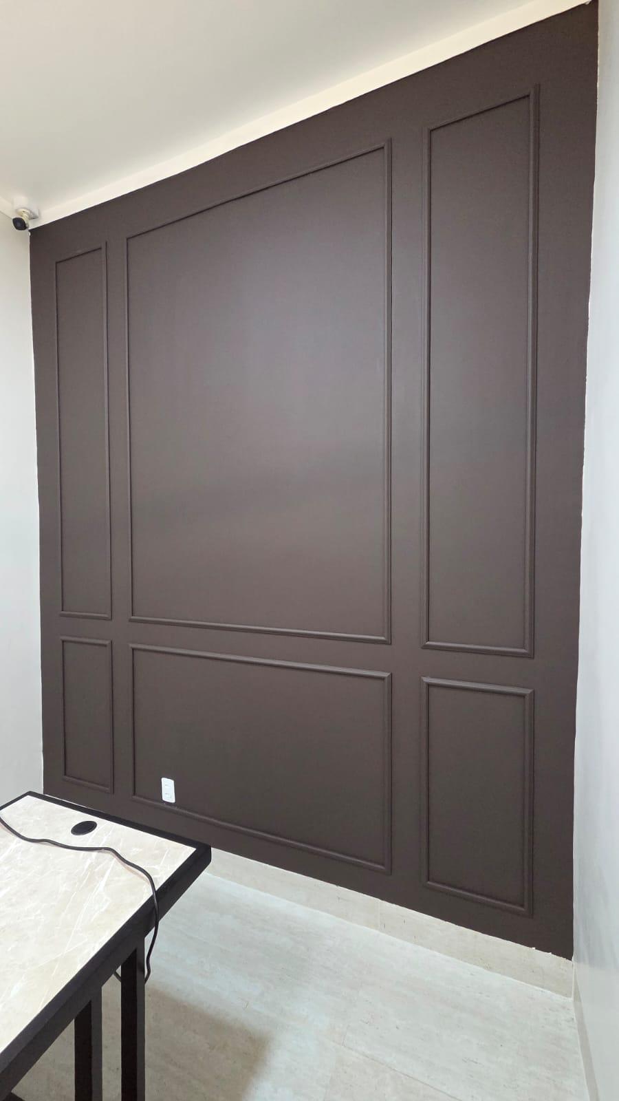 Parede com moldura Boiserie marrom instalada pela Aplik Decor