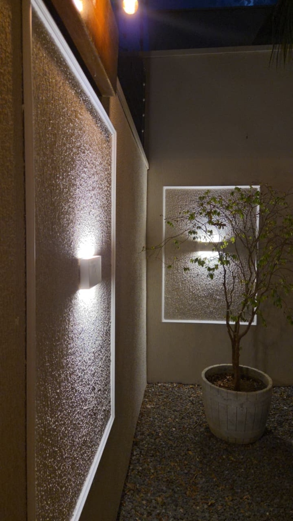 Moldura boiserie com iluminação de arandelas em parede externa